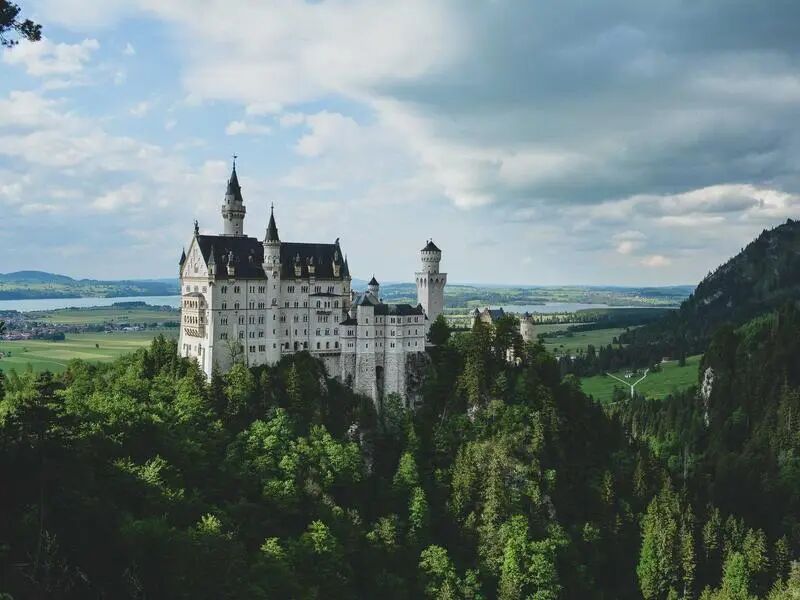 Comparison of two images (Neuschwanstein Castle vs. natural scenery) — Severe hallucination: says 'It's all coffee-related'